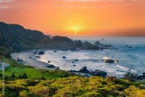 a beach with a body of water and a sunset near hotels in brookings oregon